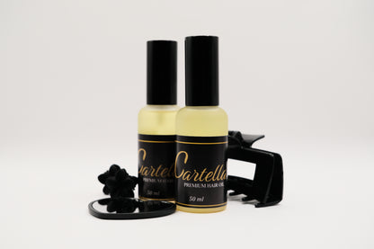 Two bottles of Cartella hair oil with a black cap on a white background